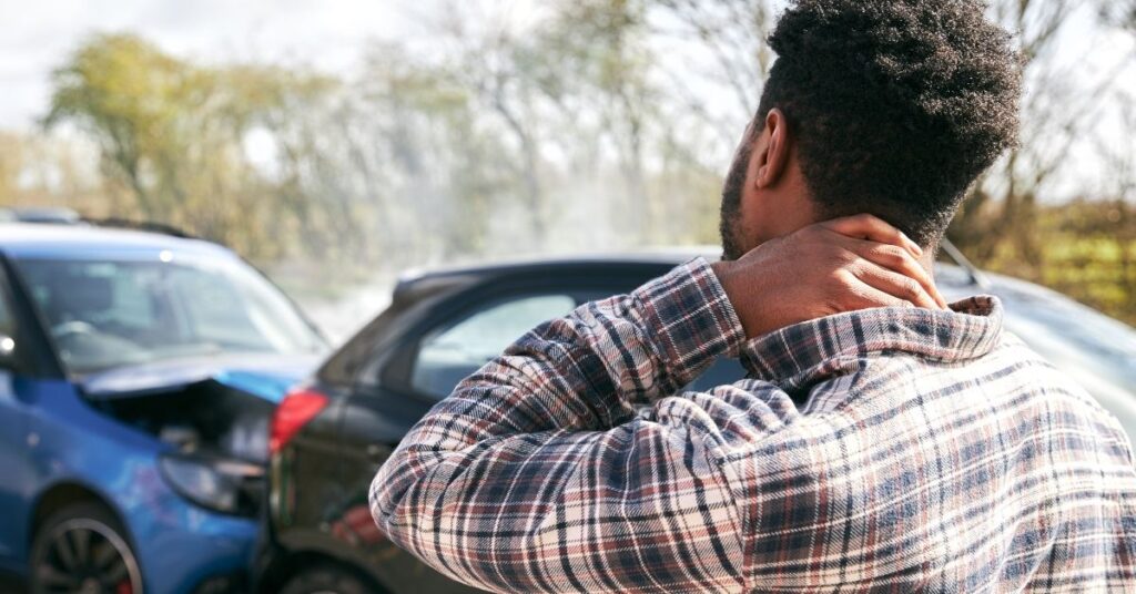 Driver of the car experiences a car accident. He is holding his neck in pain.