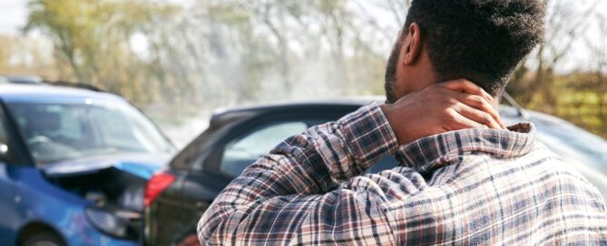 Driver of the car experiences a car accident. He is holding his neck in pain.
