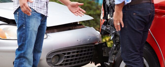 two men looking at the damage caused by a rear end car accident